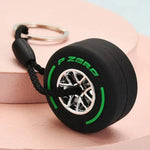 Luxury racing tire keychain featuring a stylish black tire design with green accents and a detailed wheel pattern