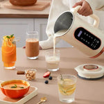 Mini soybean milk machine pouring fresh soy milk into glasses on a kitchen table